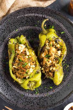 two stuffed peppers on a black plate