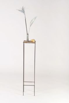 a tall metal plant stand with a flower in it's center on a white background