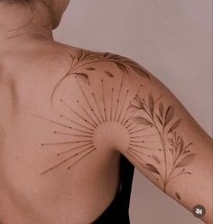 the back of a woman's shoulder with an intricate sunburst tattoo on it