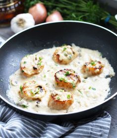 shrimp and grits in a skillet on a table with onions, garlic and parsley