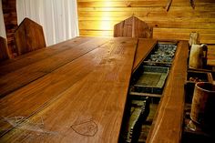 a wooden table and chairs in a room with wood paneling on the wall behind it