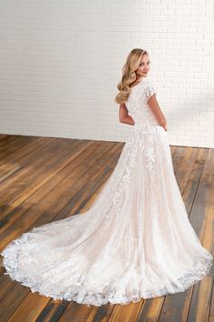 a woman in a wedding dress standing on a wooden floor with her back to the camera