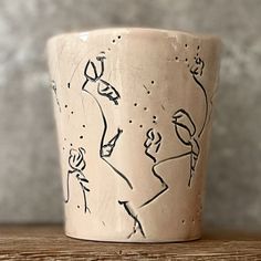 a cup with drawings on it sitting on a table