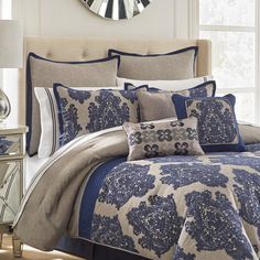 a bed with blue and white comforters in front of a clock on the wall