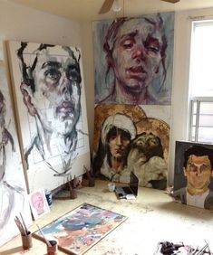 an artist's studio with several paintings on the wall