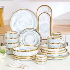 white and gold dinnerware set on counter with flowers