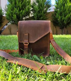 a brown leather bag sitting in the grass