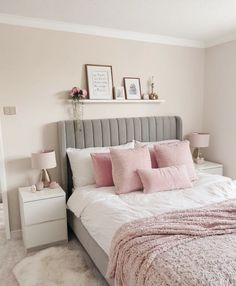 a bed with pink pillows and blankets in a bedroom