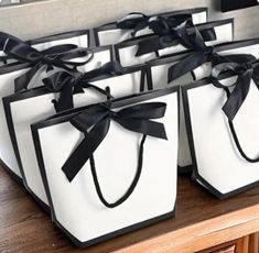 several white bags with black bows on them sitting on a table in front of a mirror