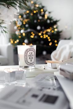 a candle sitting on top of a table next to a christmas tree