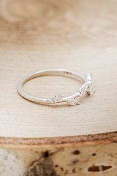 a silver ring sitting on top of a piece of wood next to a wooden table