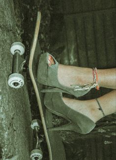 a person with their feet on a skateboard next to a tree and some wheels