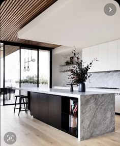 a kitchen with white cabinets and marble counter tops in front of a large open window