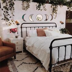 a bedroom with white bedding and lots of plants hanging on the wall above it