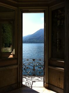 an open door leading to a lake with mountains in the background