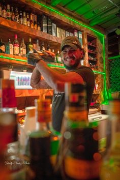 a man with red face paint on his face behind a bar filled with liquor bottles