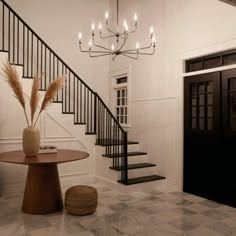 a foyer with a chandelier, table and vase on the floor next to it