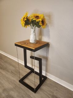 a vase with sunflowers is chained to a small table on the floor next to a wall