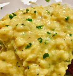 a white plate topped with macaroni and cheese covered in chives on top of meat