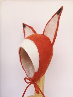 a red and white fox hat on top of a wooden headdress with an orange ribbon