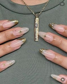 a woman's hands with gold and pink nail polishes on her nails, holding a bar necklace