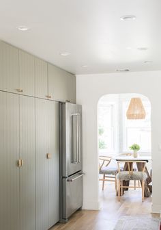 a kitchen with white walls and wood flooring next to a dining room table in the center