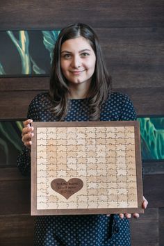 a woman holding up a wooden puzzle with a heart on it