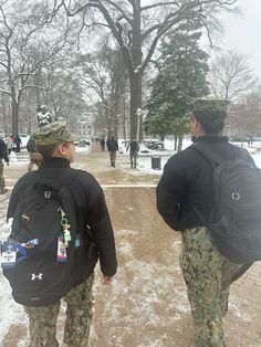 two people with backpacks walking in the snow