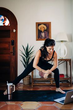 a woman is doing yoga on the floor in front of her laptop and coffee mug