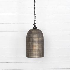 an old bell hanging from a chain on a white wall