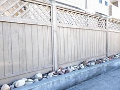 a man riding a skateboard down a street next to a wooden fence and building