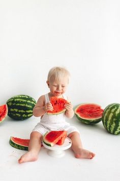 a baby sitting on a potty with slices of watermelon