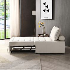 a white couch sitting on top of a hard wood floor next to a table with flowers