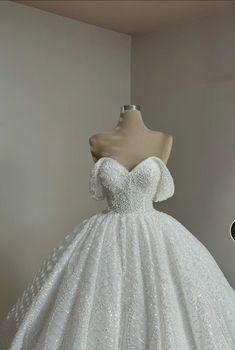 a white wedding dress is on display in a room with a mannequin's head