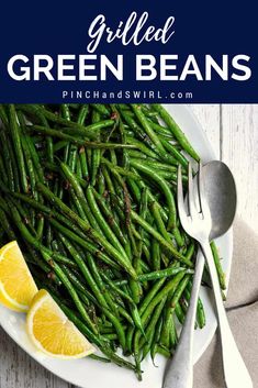 grilled green beans on a white plate with lemon wedges