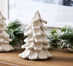 three ceramic christmas trees sitting on top of a wooden table