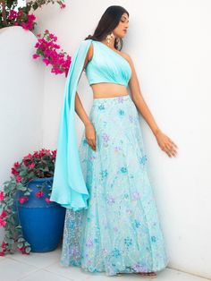 A two-piece Blue floral multi sequins lehenga with light blue drape blouse from the Shrena Hirawat collection. This beautiful cotton satin blue drape blouse is paired with a semi satin georgette blue floral multi sequins lehenga. The multi sequin floral embroidery with cancan, and butter crepe lining enhance this lehenga set. This outfit is completed with a blue dupatta attached to the drape blouse. Blue Sequined Floor-length Pre-draped Saree, Blue Traditional Drape Set For Spring, Spring Blue Traditional Drape Set, Blue Saree Sets For Spring, Spring Blue Saree Set, Light Blue Choli With Resham Embroidery For Parties, Light Blue Party Choli With Resham Embroidery, Blue Lehenga For Spring Party, Spring Bollywood Lehenga With Traditional Drape