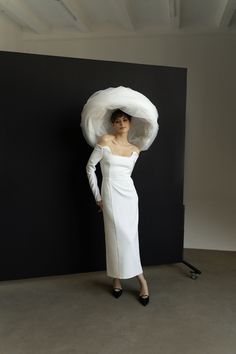 a woman wearing a white dress and hat