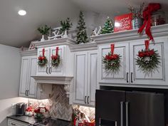 a kitchen decorated for christmas with wreaths on the cabinets and decorations hanging from the ceiling