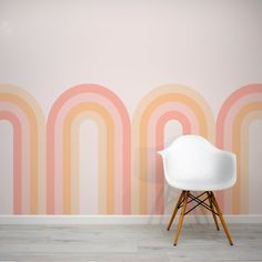 a white chair sitting in front of a wall with a rainbow painted on it's side