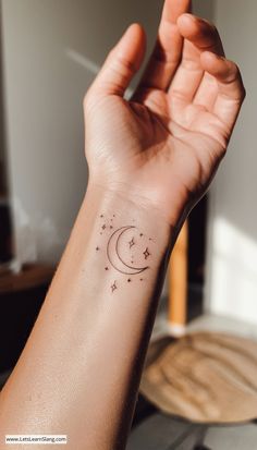 a person's arm with a small star and moon tattoo on the left wrist