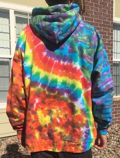 a person standing in front of a building wearing a tie dye hoodie