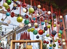 christmas decorations hanging from the ceiling in an indoor area with red and green ribbons around them