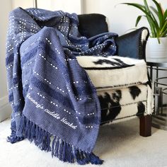 a blue and white blanket sitting on top of a chair next to a potted plant