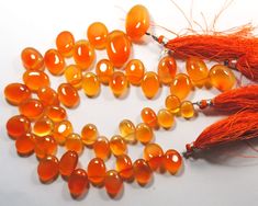 several orange beads with tassels on a white surface