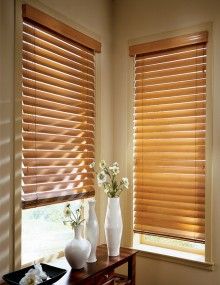 two vases with flowers are sitting on a table in front of the window blinds