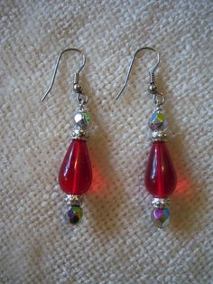 "Beautiful handmade drop earrings measure 2 1/8\" long. The earrings are in a silver tone setting and feature a red center drop bead with silver tone and iridescent beads on top and bottom. These earrings have a lot of sparkle and would dress up any outfit." Red Teardrop Earrings With Dangling Beads, Red Beaded Drop Crystal Earrings, Red Beaded Crystal Drop Earrings, Nickel Free Red Drop Earrings, Nickel-free Red Beaded Sterling Silver Earrings, Red Beaded Sterling Silver Earrings, Red Sterling Silver Nickel-free Beaded Earrings, Red Metal Dangle Beaded Earrings, Red Metal Beaded Earrings For Pierced Ears