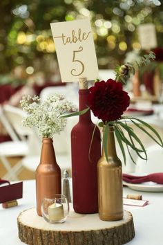 there are three bottles with flowers in them and a table number on the top one