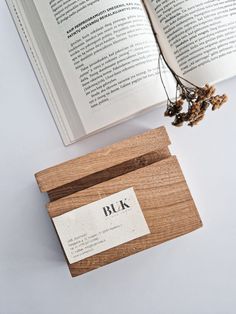 an open book sitting on top of a table next to a wooden box with a label