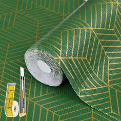 a roll of tape next to a ruler and measuring tape on top of a green wallpaper